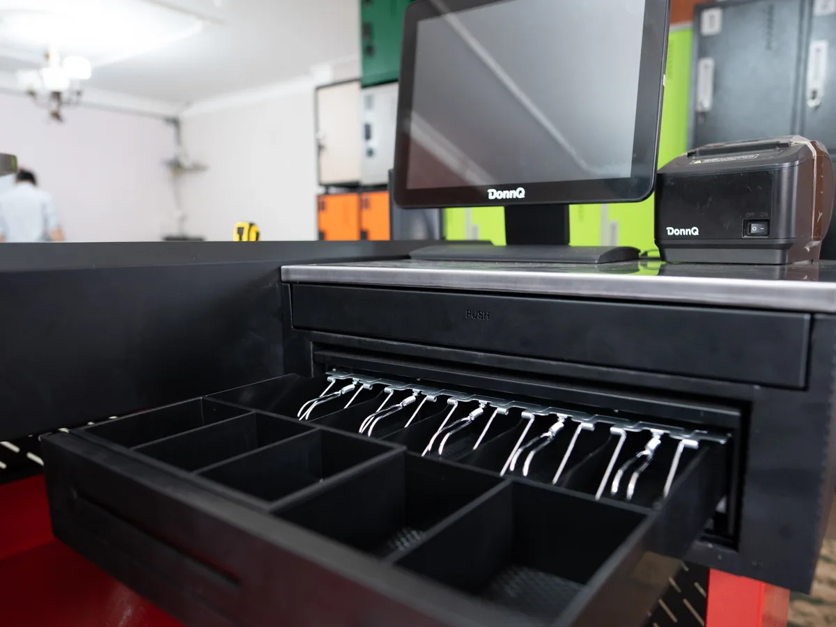 Counter metálico negro y rojo con puesto para caja registradora y monitor